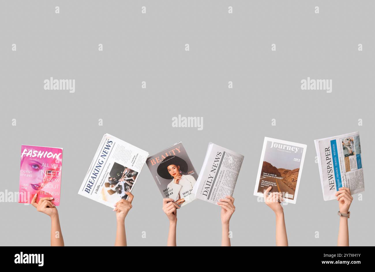 Female hands with different magazines and newspapers on grey background Stock Photo