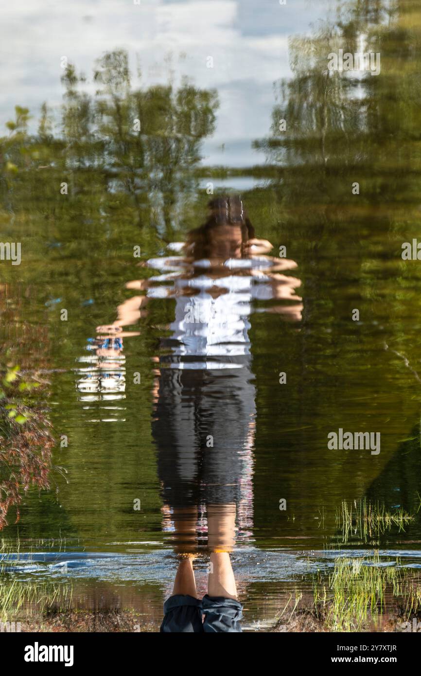 Anonymous woman walking a flooded boardwalk in the Mastbos, a small forest located on the edge of Breda, the Netherlands. Stock Photo
