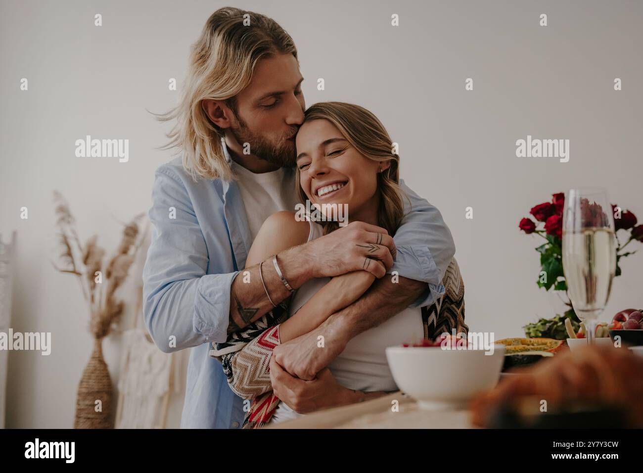 Young loving couple embracing and kissing while enjoying romantic dinner at home together Stock Photo