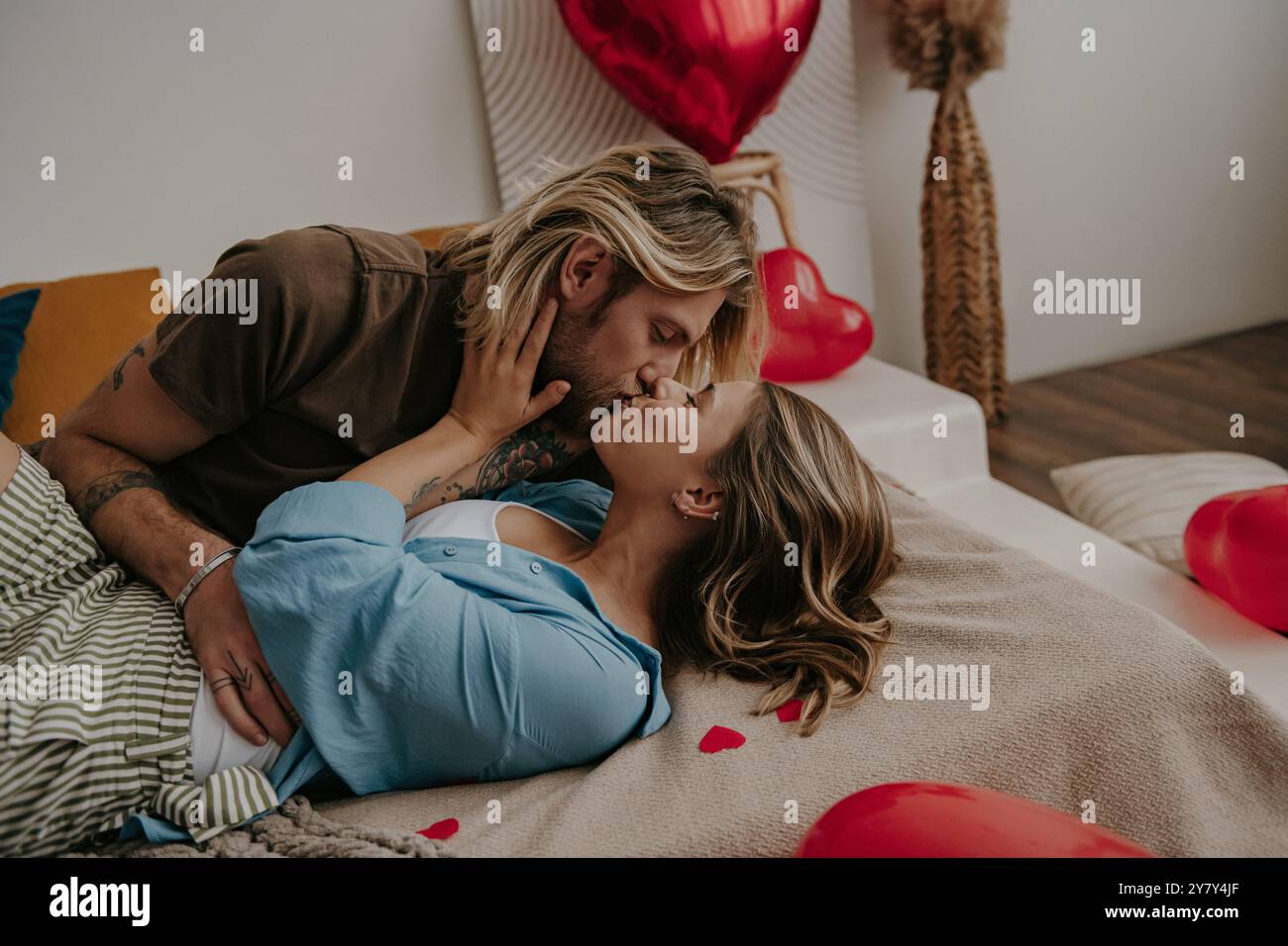 Passionate loving couple embracing and kissing while lying down in bed ...