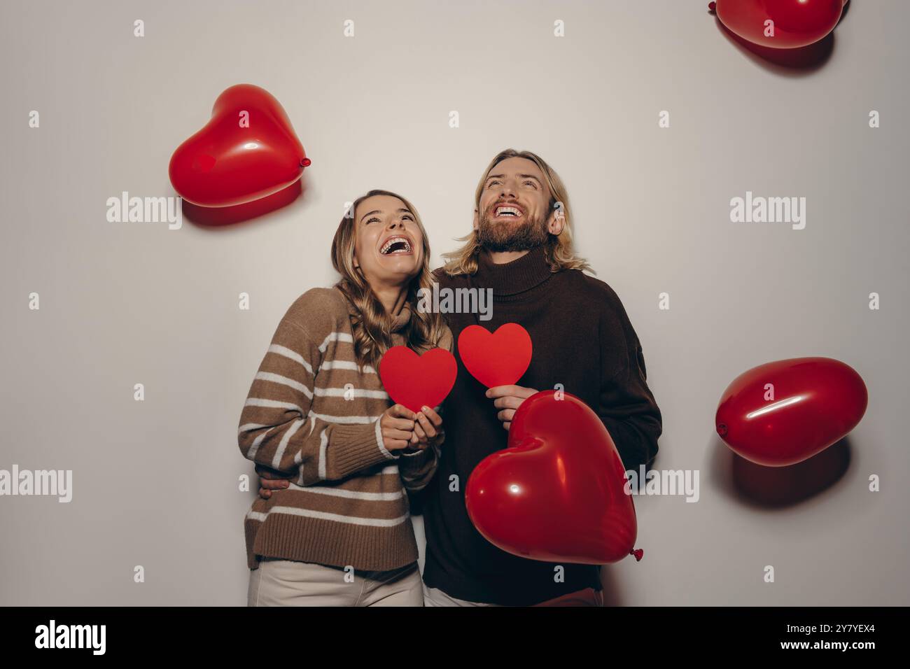 Joyful loving couple holding heart shape Valentines cards on beige ...