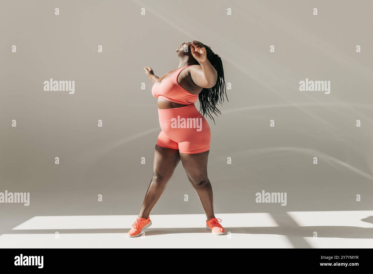 Stretch Routine For Plus Size Full length of active African plus size woman in sportswear doing ...