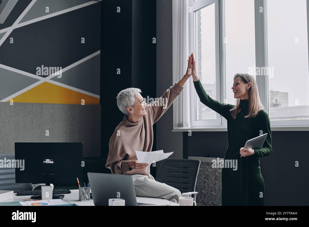 Two happy women giving high five to each other while standing in the ...