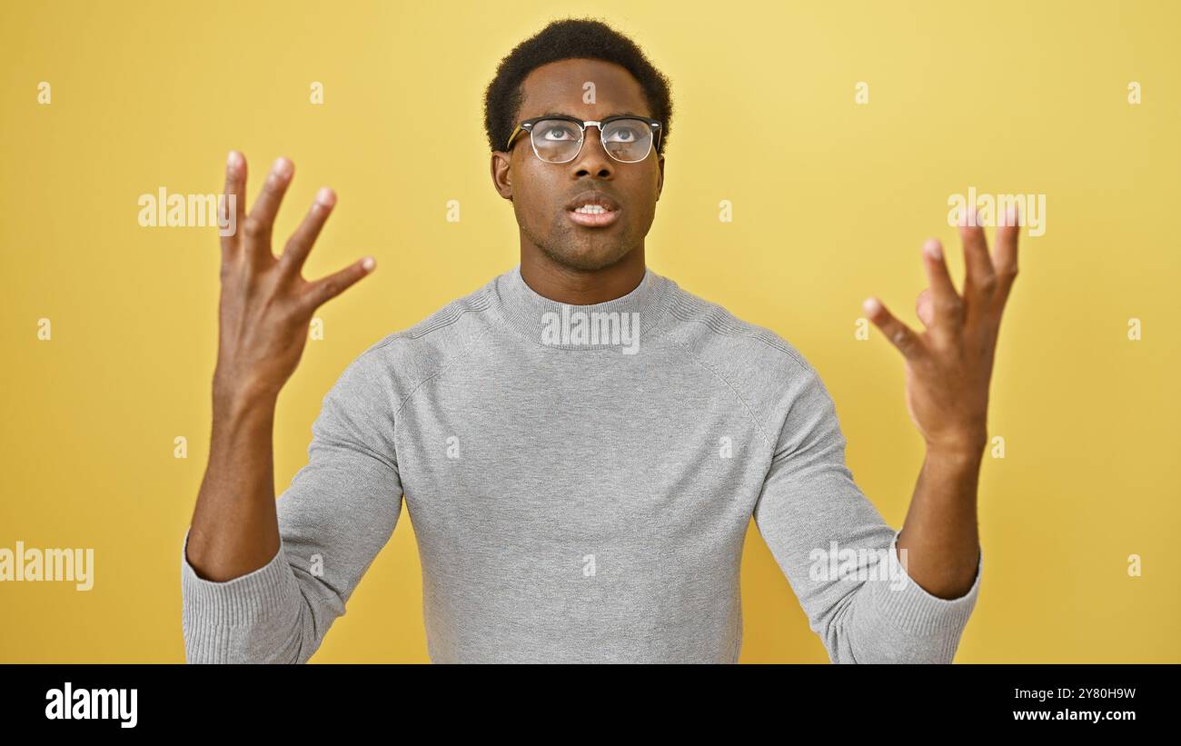 Perplexed african american man gesturing with hands against a yellow ...