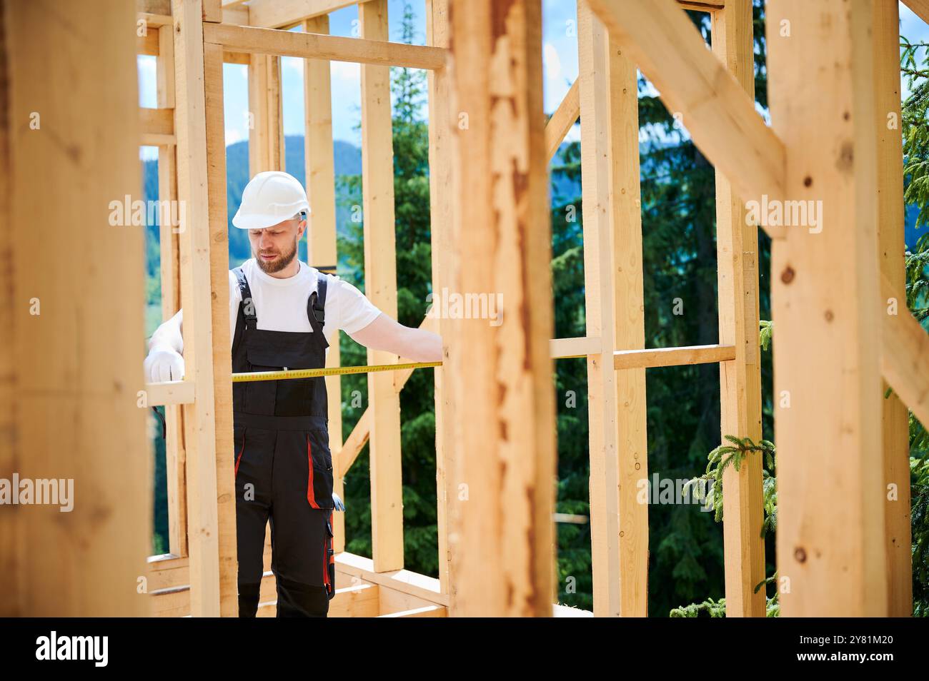 Carpenter building timber-framed house. Man measures distances with ...