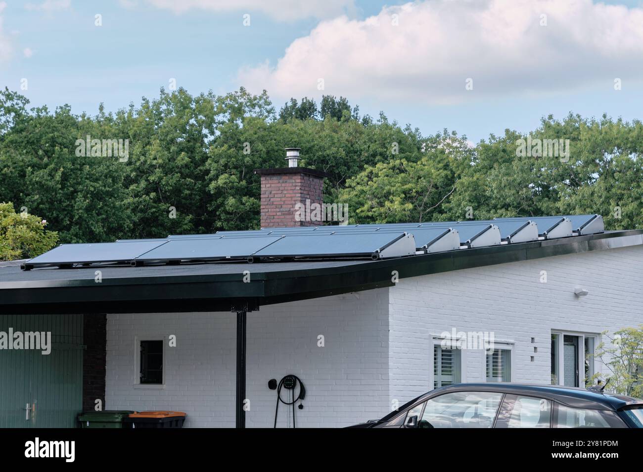 an electric vehicle charger at a residential house equipped with solar panels. A modern example of sustainable living and renewable energy solutions i Stock Photo