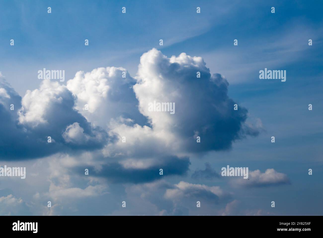 Cloudy blue sky, white clouds background with deep blue sky. Wallpaper with sunlight. Texture, pattern idea concept. Horizontal photo. No people. Stock Photo