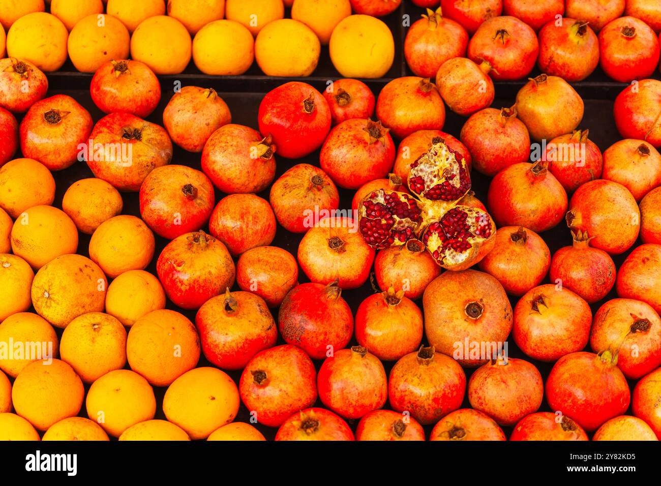 A vibrant assortment of oranges and pomegranates displayed on a table Stock Photo