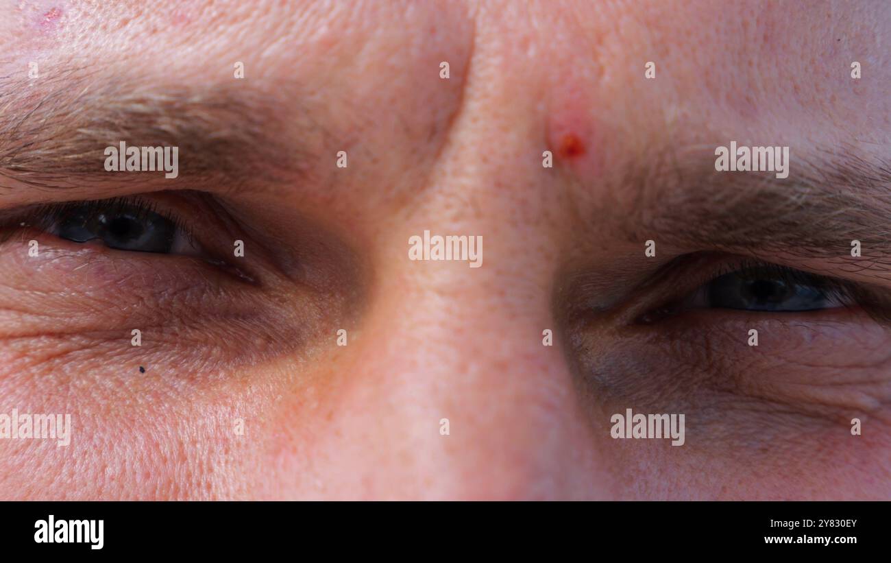Close up to upset male face looking into camera with a disappointing sight. Upset facial expression of man with blue eyes. Unhappy gaze of despairing Stock Photo