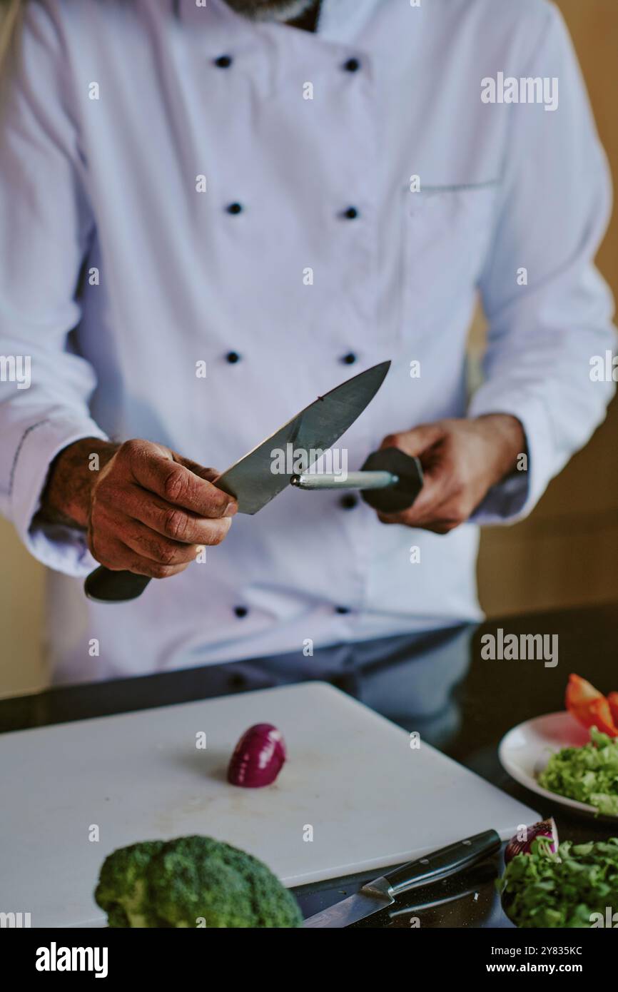 Unrecognizable male chef sharpening knife carefully while preparing ingredients Stock Photo