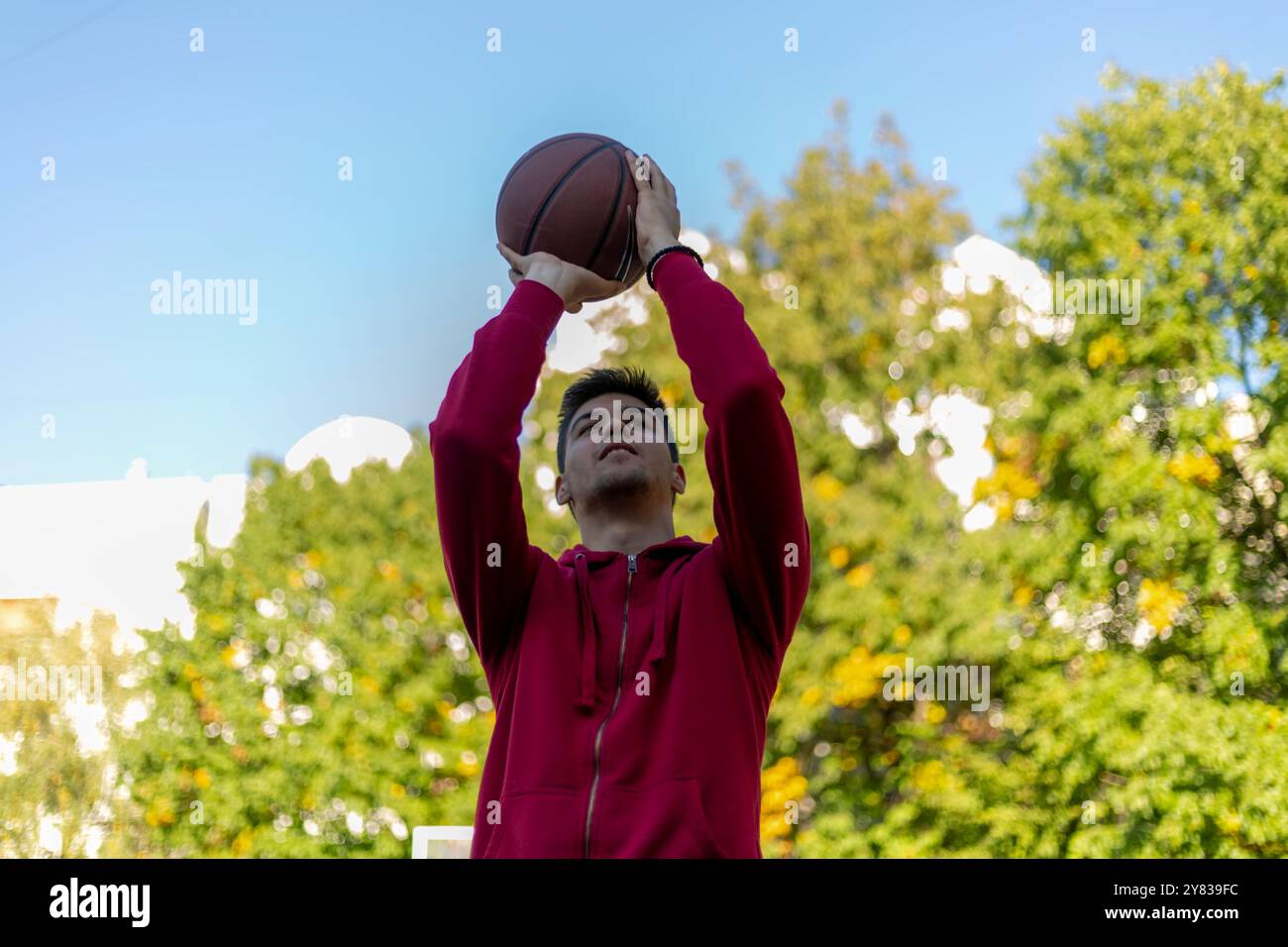 Handsome basketball player shooting a ball through the hoop while