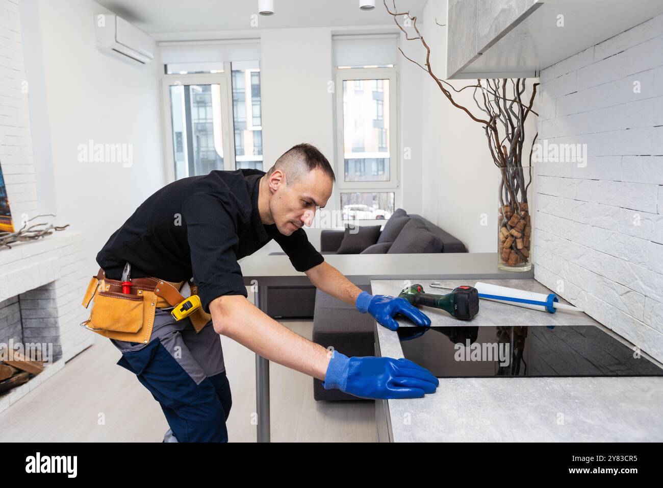 craftsman installs hob in kitchen. Household Appliance Installation Services Concept Stock Photo