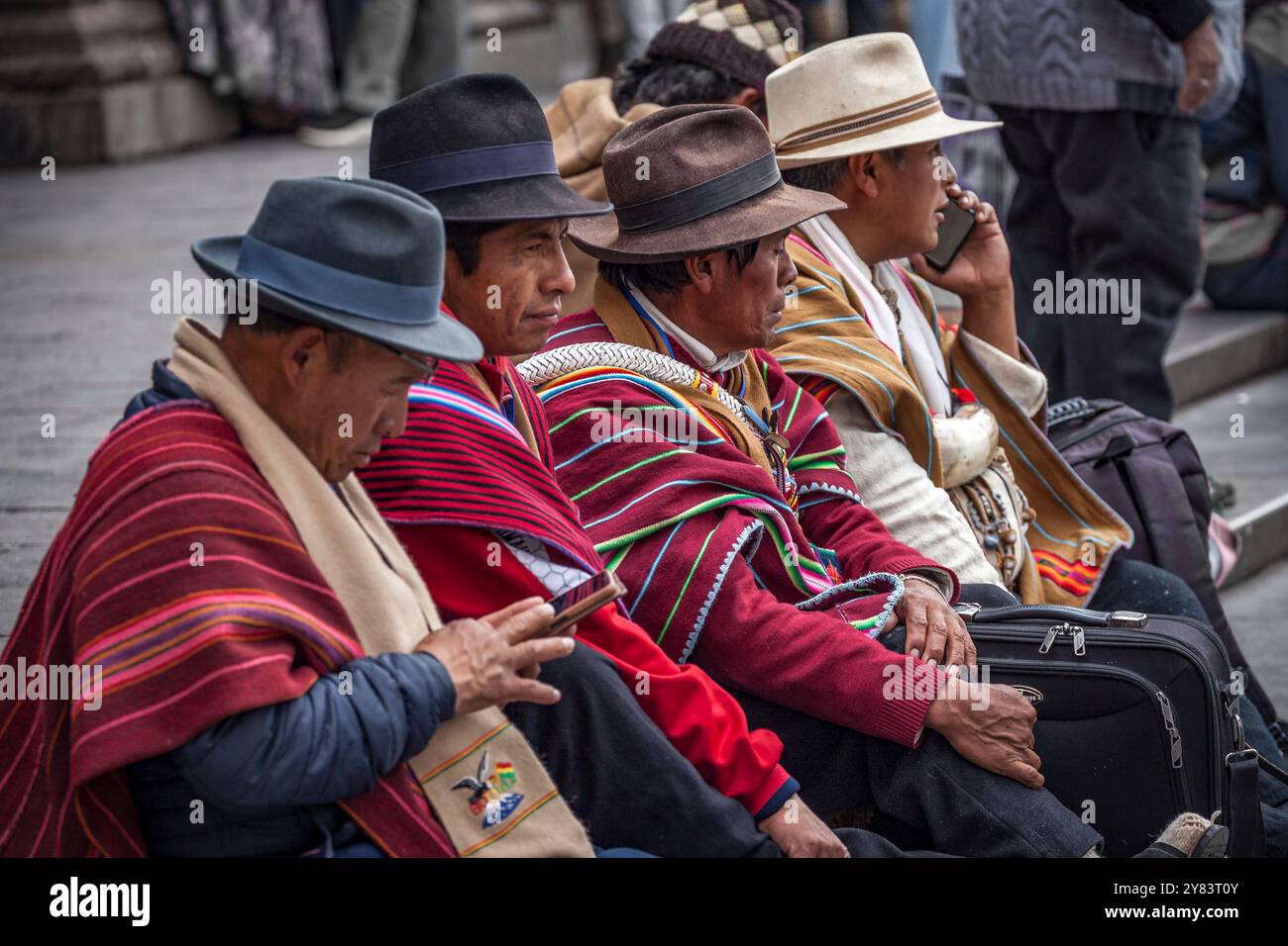 Local Bolivian men wearing traditional fedoras and mantas, Plaza Mayor ...