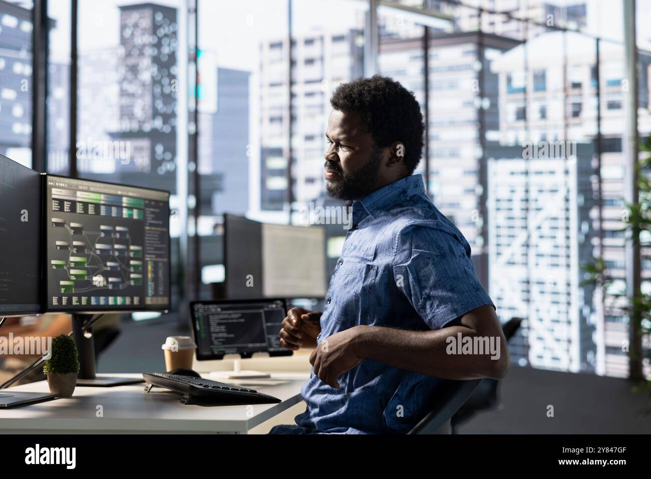 Programmer in pain, suffering muscle sprain while developing machine learning APIs solving complex problems. Man feeling backache from sitting on desk chair while training predictive models Stock Photo
