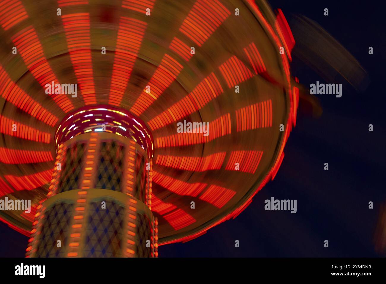 Carrousel Rides Red An illuminated carousel in motion at night, glowing red and creating a ...