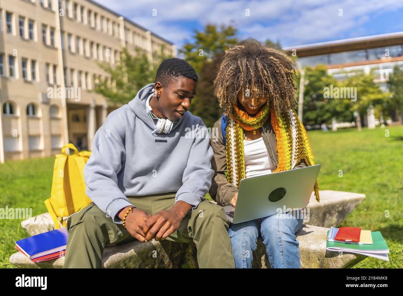 Multiracial students doing homework using laptop sitting outside the ...