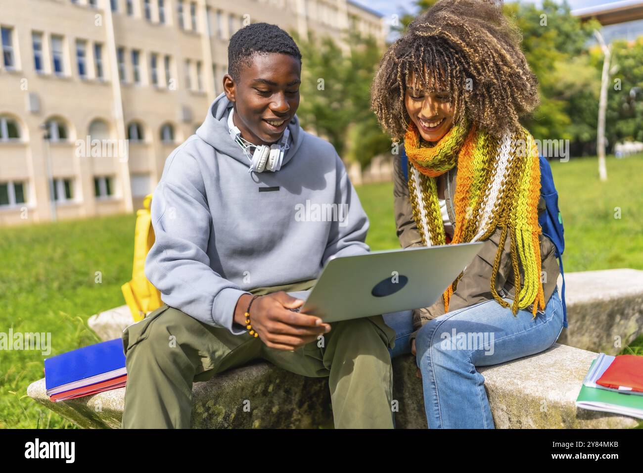 Smiling young multiethnic students studying together with a laptop ...