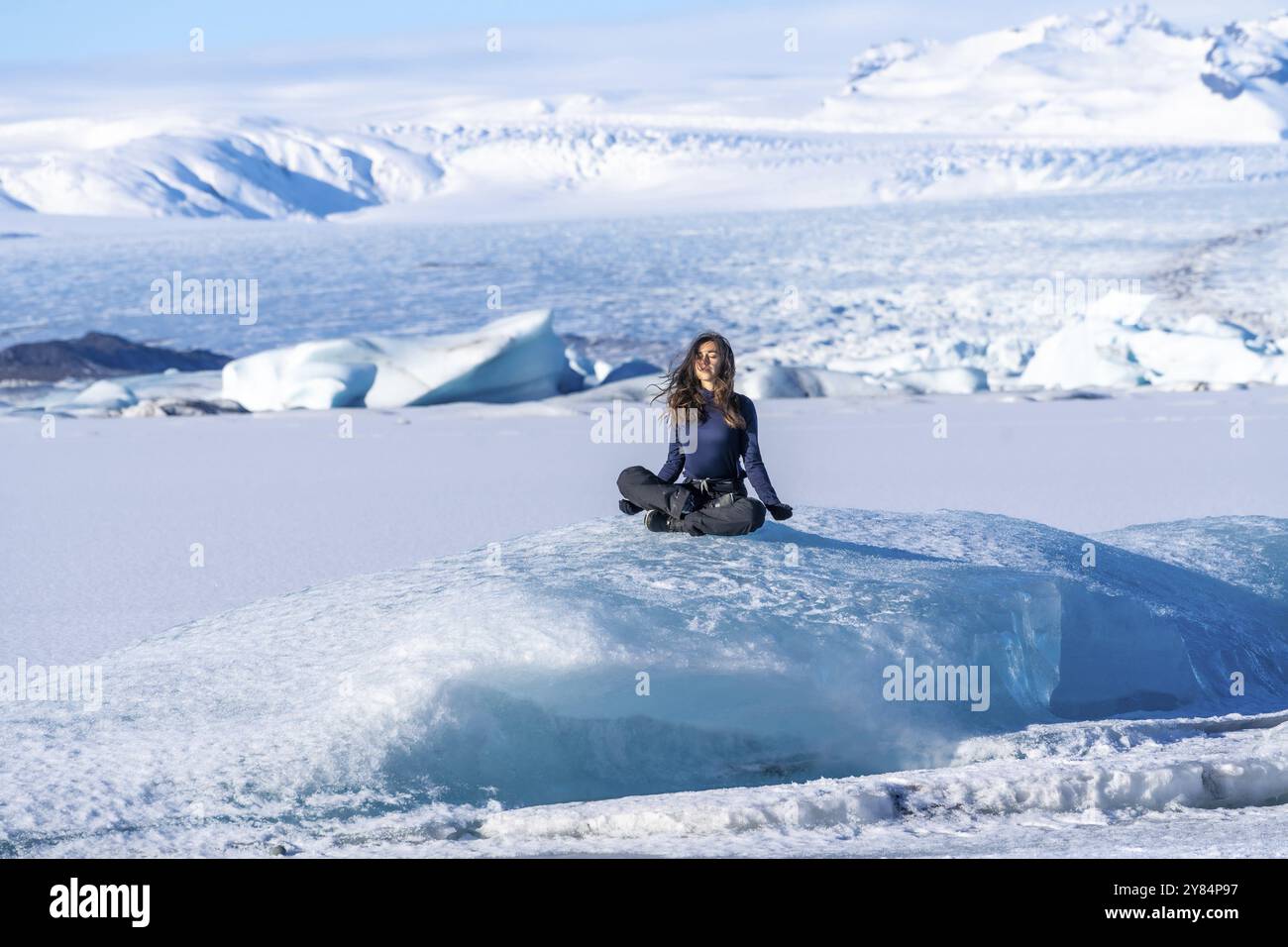 A woman is sitting on a large block of ice the ice is surrounded by