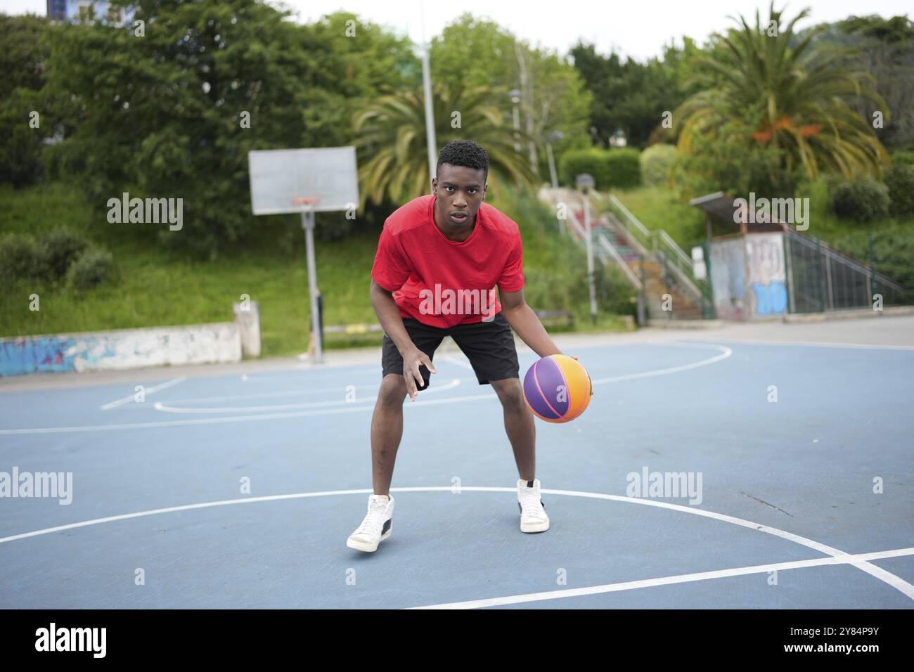 Portrait of a young african man dribbling a basketball ball at the outdoor courtyard Stock Photo