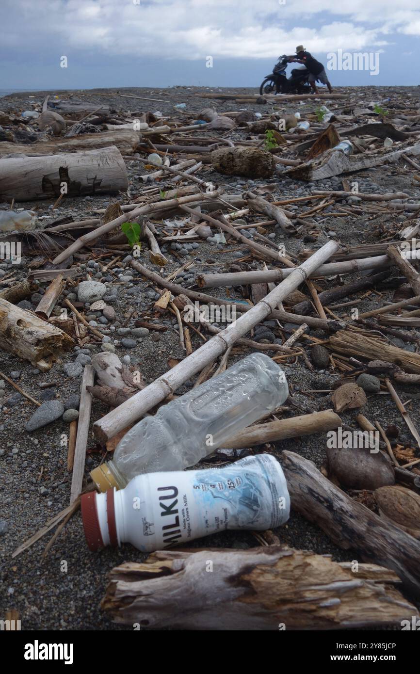Pushing motorbike through trash on beach, Una Una Island, Togean Islands, Sulawesi, Indonesia. NO MR or PR Stock Photo