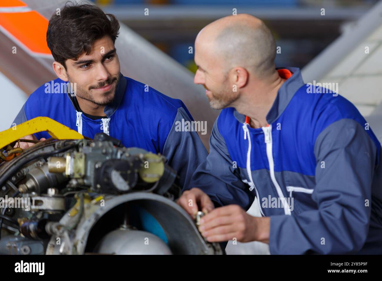 two engineers talking while working in a hangar Stock Photo