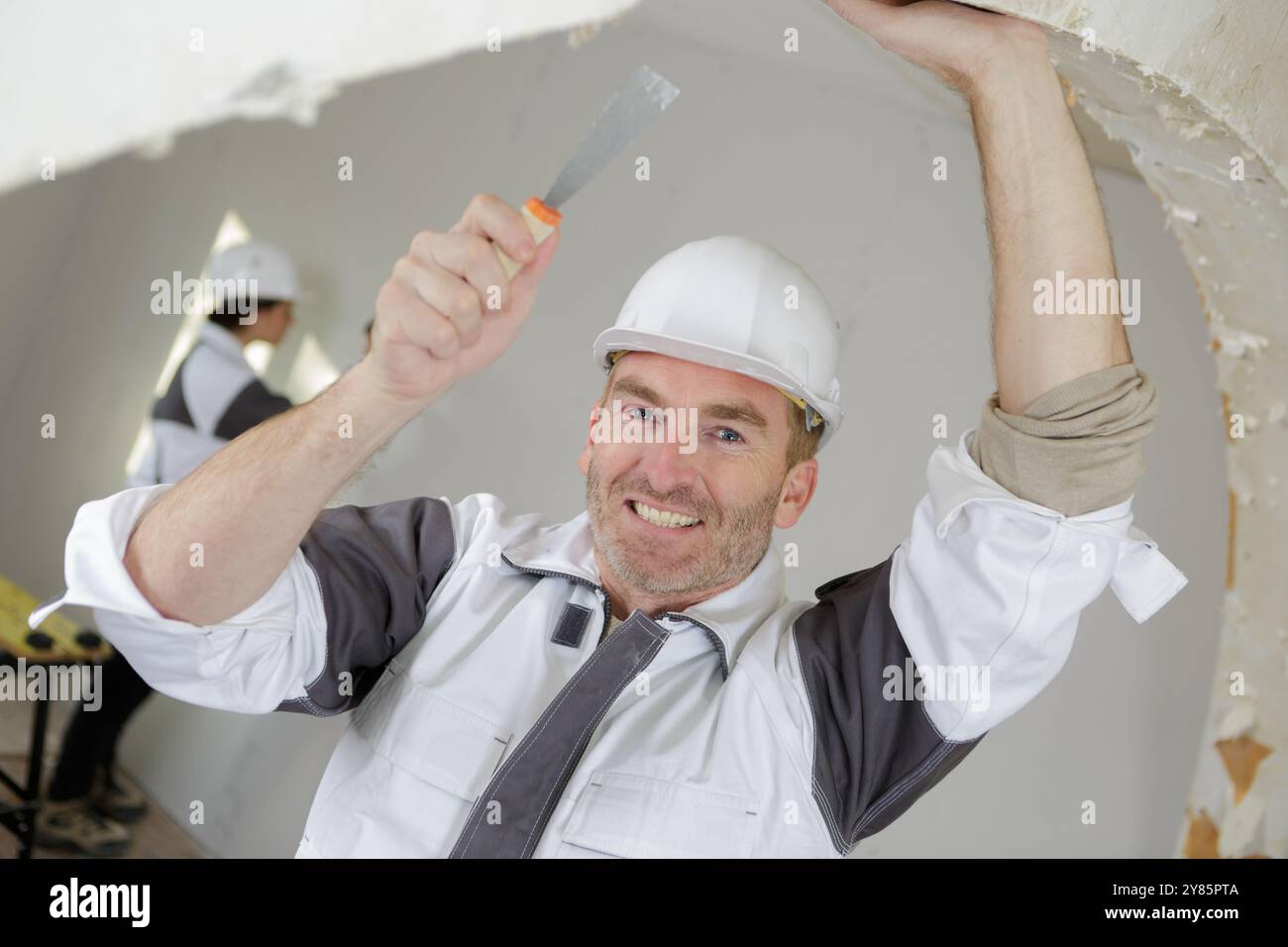 smiling builder in hardhats with tools indoors Stock Photo