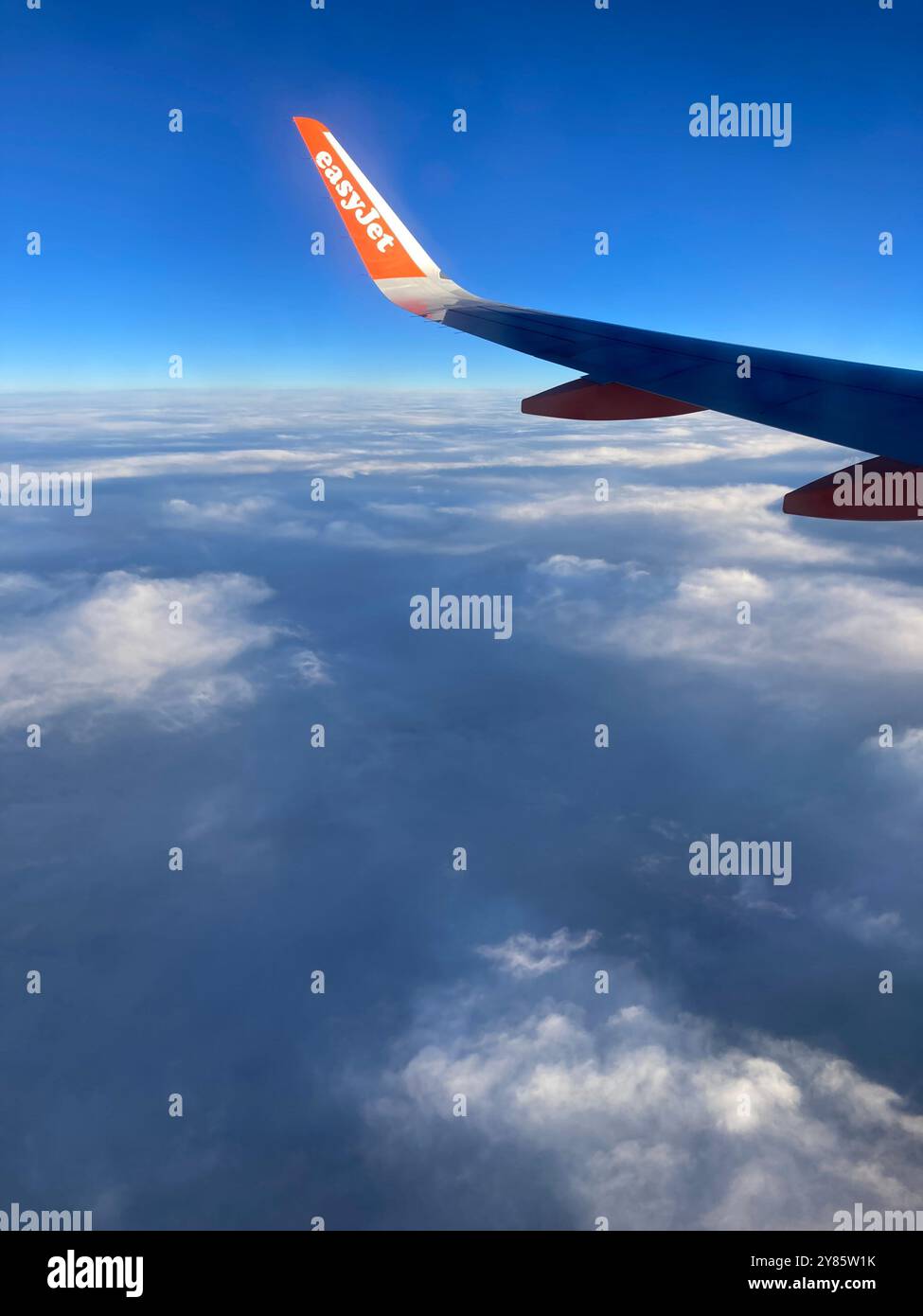 The wing of an Easyjet Airbus 320 plane flying above the clouds. - Smartphone Captured Stock Image