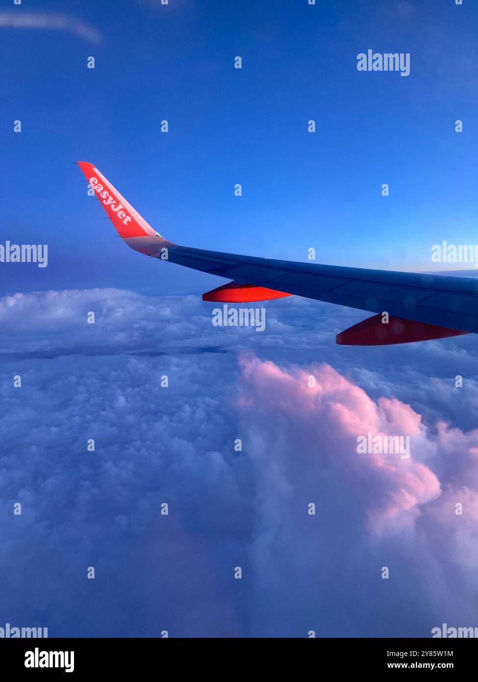 The wing of an Easyjet Airbus 320 plane flying above the clouds. - Smartphone Captured Stock Image
