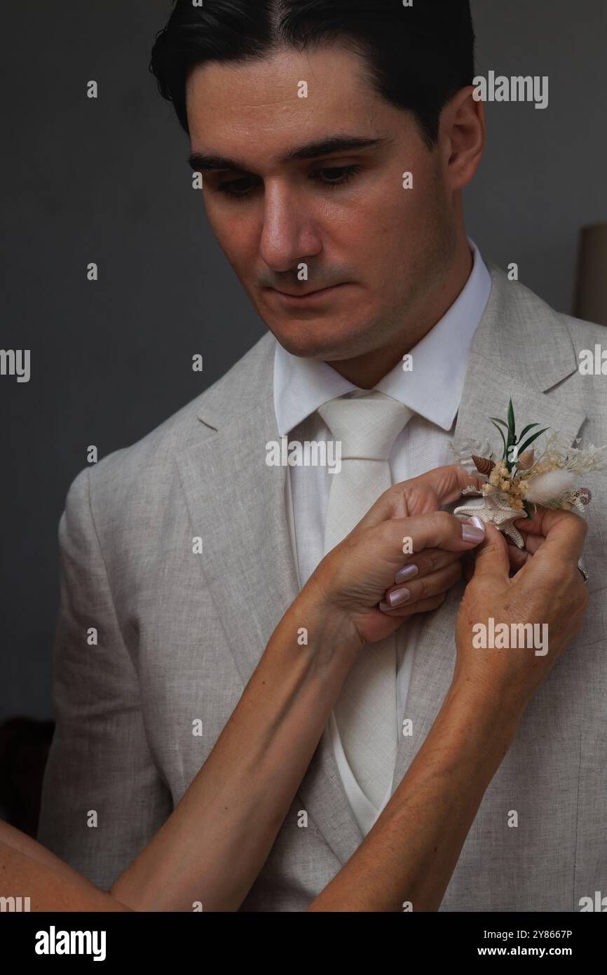 Groom receiving the flower pin or boutonniere on his lapel with a serious expression, Spain Stock Photo