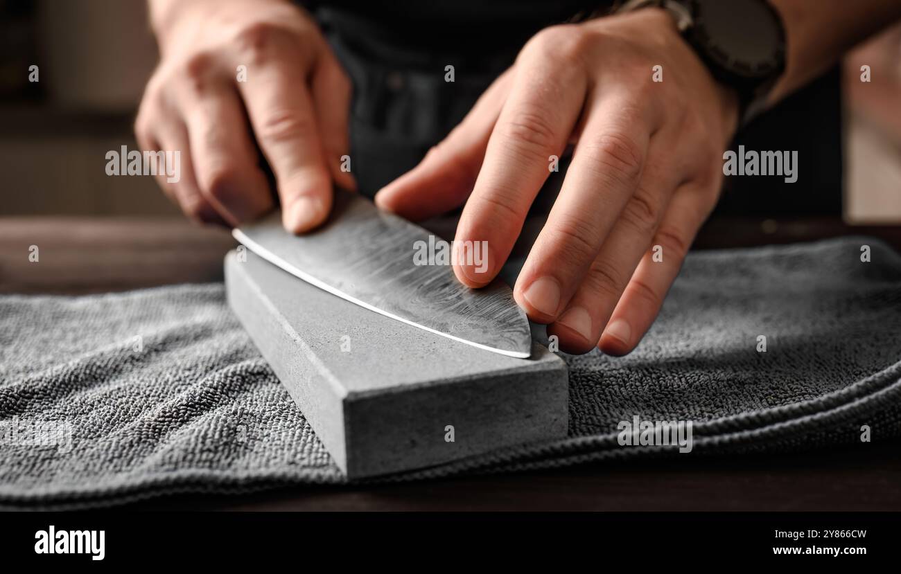 Man sharpening a knife with whetstone, closeup view Stock Photo