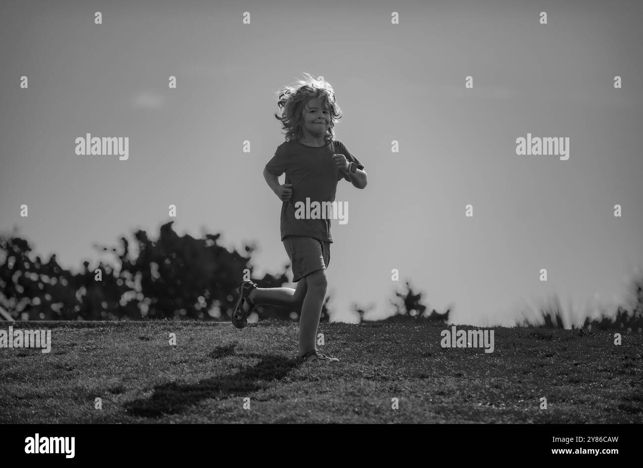 Cute boy running on green grass and blue sky. Healthy sport activity ...