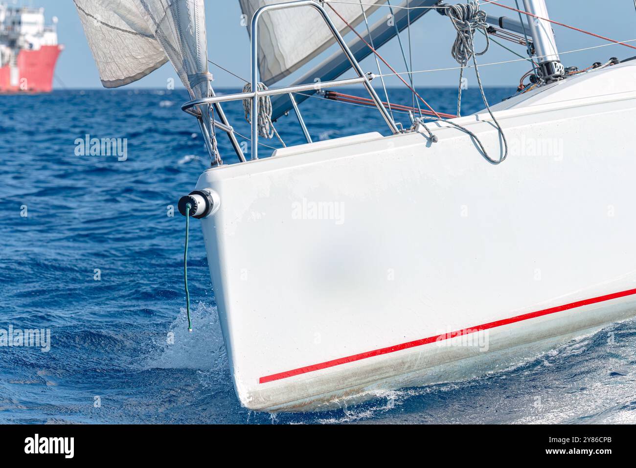 White sailboat cutting through blue ocean water on a sunny day Stock Photo