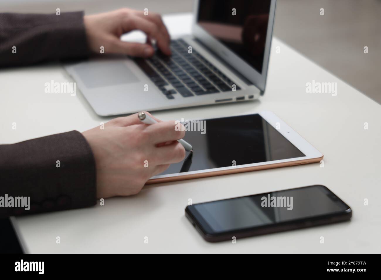 Businessman using different devices at white table indoors, closeup. Modern technology Stock Photo