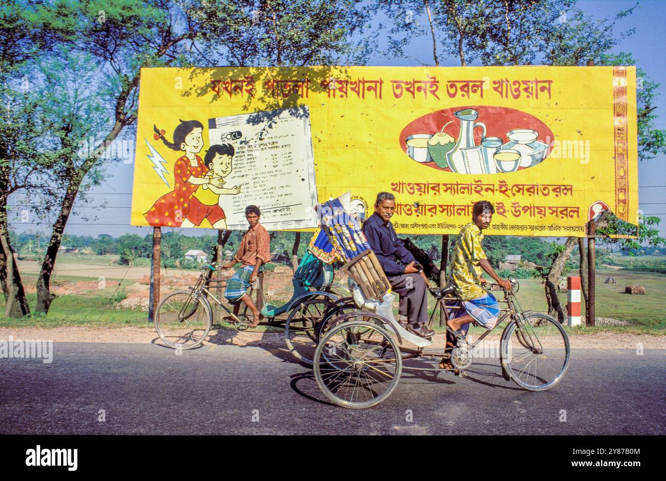 Bangladesh, rickshaw passes a billboard emphasizing the importance of healthy eating. Stock Photo