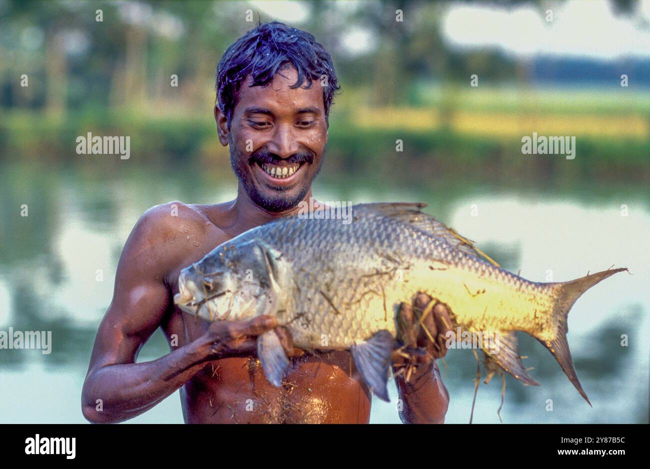 Bangladesh, Manikganj, farmer with farmed fish from his fishpond, set up with a micro loan. Stock Photo