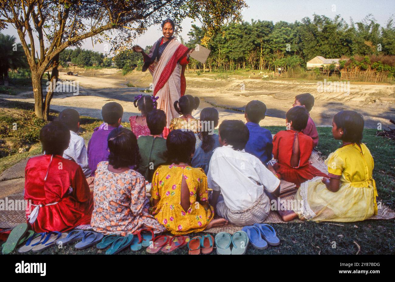 Bangladesh, Betila, Due to the heat, a teacher teaches outside next to a dry riverbed. Stock Photo