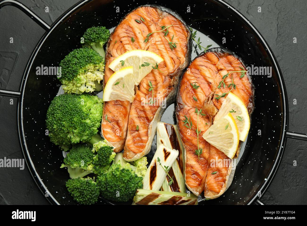 Tasty grilled salmon steak with lemon and vegetables on dark textured ...