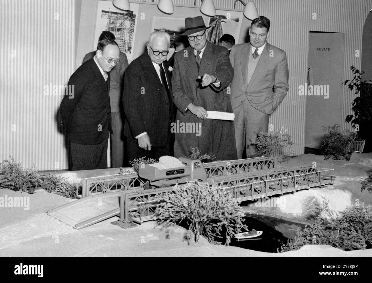Sir Donald Bailey Erects One Of His Own Bridges:Photograph Shows: Sir Donald Bailey seen standing beside a scale model of one of the famous bridges bearing his name at the public works and municipal services Exhibition at Olympia this morning.Sir Donald Bailey, the brilliant wartime inventor of the bridge bearing his name, today said a visit to the public works and municipal services exhibition, now in progress at Olympia, on one of the stands, Sir Donald Erected a model of one of his famous bridges. November 18, 1954. (Photo by Fox Photos). Stock Photo