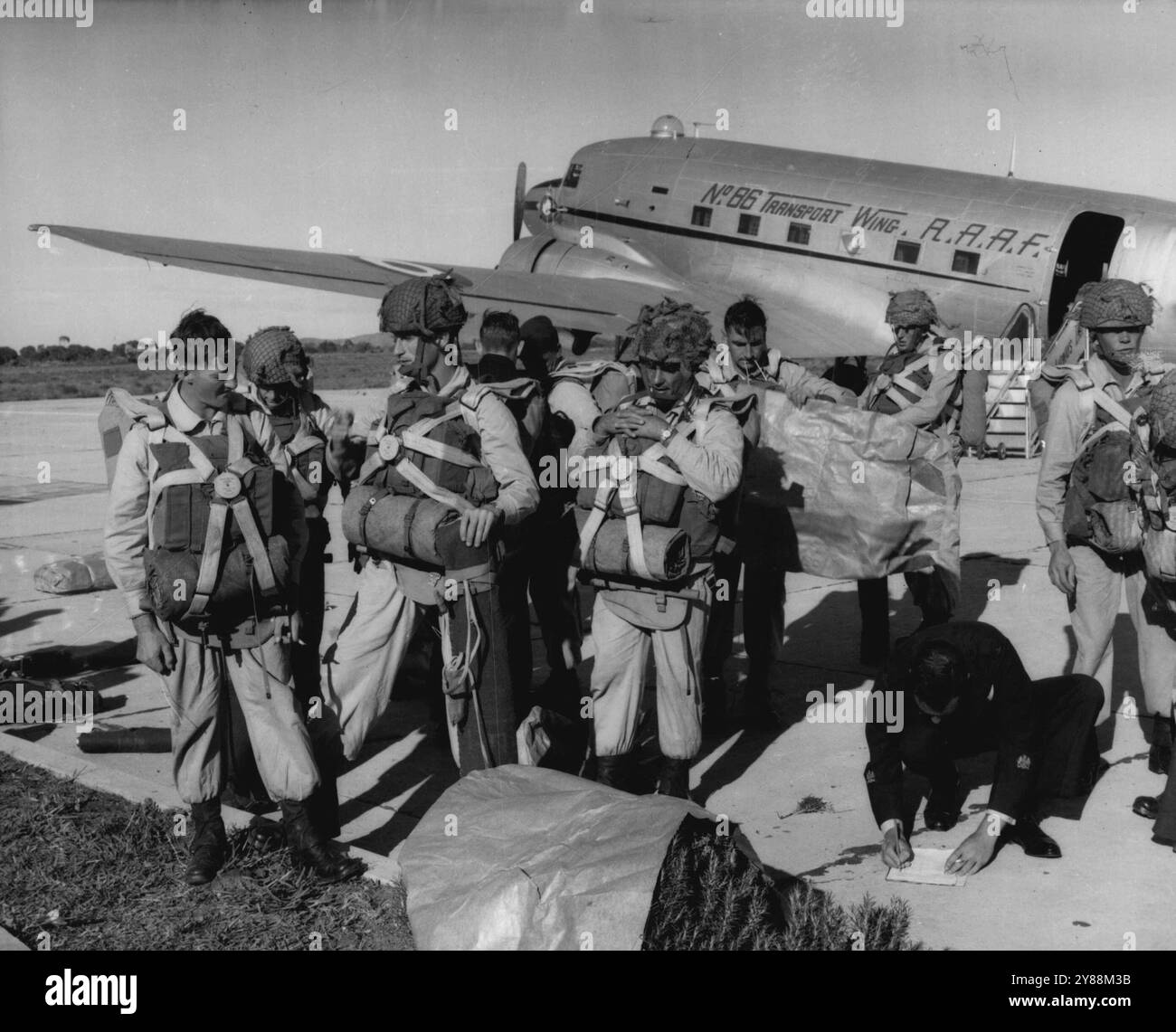 This week members of the airborne platoon of the Royal Australian Regiment were dropped from a Dakota aircraft at a height of 800 feet near Lincoln Park, South Australia, where they took part in an exercise with K CMP ground troops, Lincoln Park is a training area for troops. Here the paratroops are shown checking their chutes at Whyalla before the drop. May 20, 1955. Stock Photo