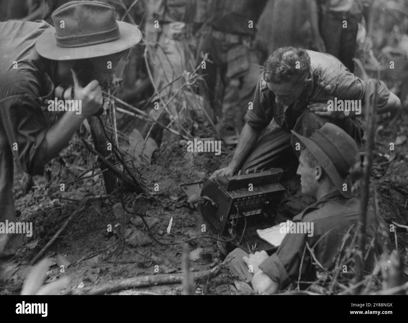 Officers of a sixth Australian Division infantry battalion keeping in communication with sections by field telephone during the successful attack on Mt. Shiburangu in the Wewak area. July 10, 1945. (Photo by Australian Official Photo). Stock Photo