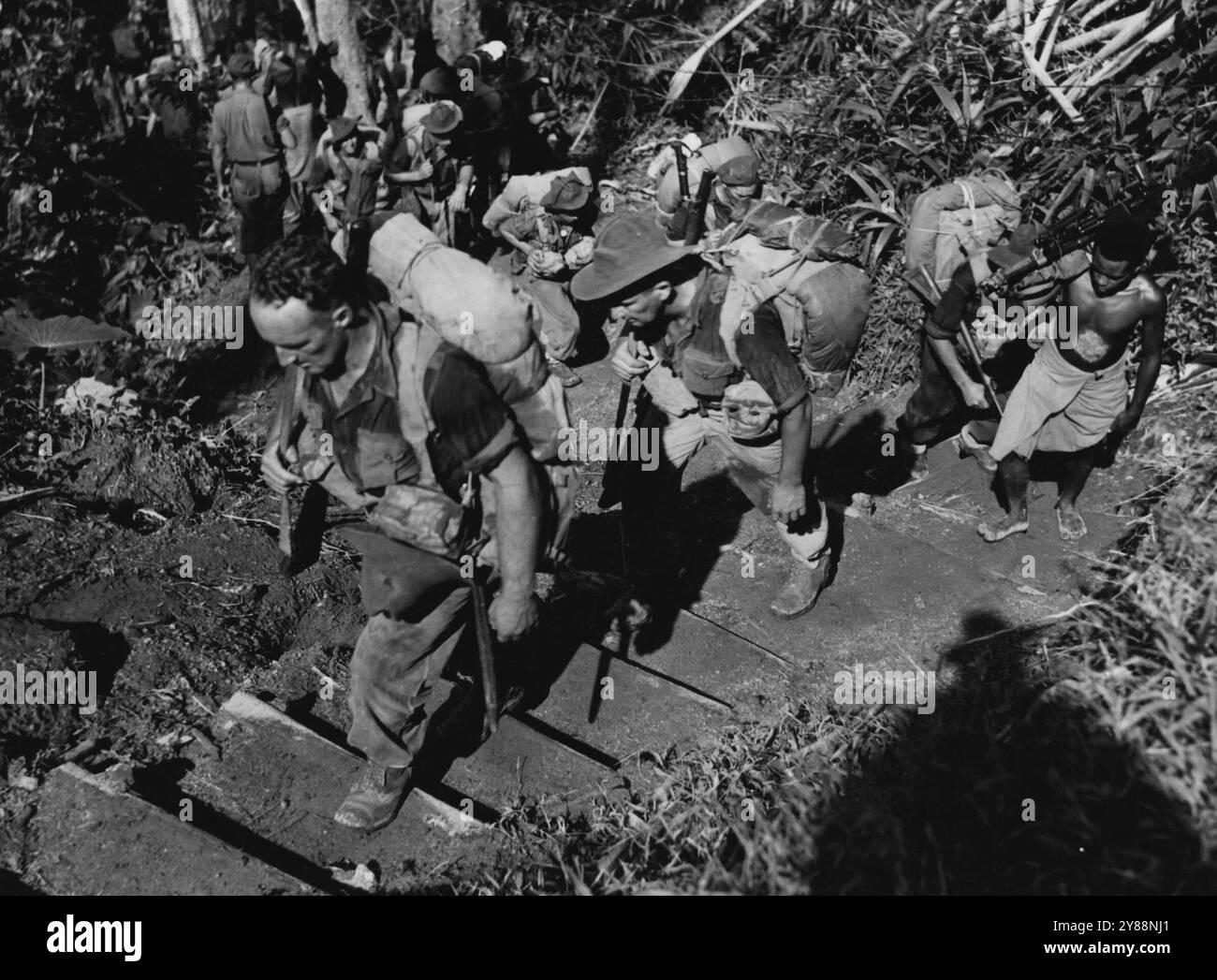 Australian infantrymen heading ***** forward positions have to climb about 3,000 ft. over mountainous country similar to that experienced in the Owen Stanleys in New Guinea. Steps have been hocked out on the slopes of the hills to facilitate progress on foot. February 13, 1945. (Photo by Australian Official Photo). Stock Photo