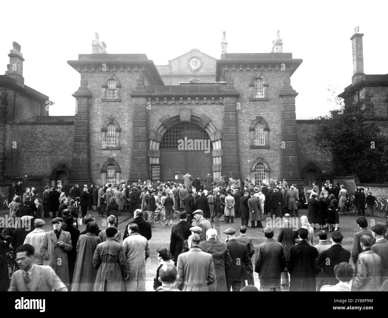 The scene outside Wandsworth prison London this morning January 28 at 9 a.m. The hour of the hanging of Derek William Bentley aged 10. For the murder of police Constable Sydney Miles at Croydon last year. An official brought out the notice of Bentley's death and the crowd booed and smashed the glass in front of the notice board by hurling coins at it (in place of stones). January 28, 1953. (Photo by Associated Press Photo). Stock Photo