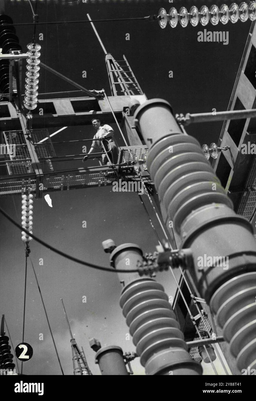 The switchyard of the Munyang powerhouse show in the wires and isolators. Mr. K. Cribb, electrical supervisor, walking along the catwalk. The isolator carries 132,000 volts. February 28, 1955. (Photo by Short/Fairfax Media). Stock Photo