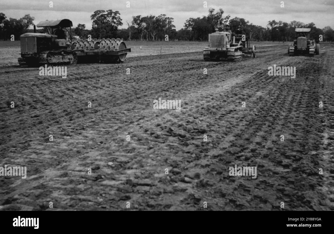 Three of the many operations in the building of a runway. On the left a sheep's foot roller consolidates the graded, gravelled surface. Centre a grader levels gravel distributed over the surface by the tractor-drawn scoop which now operates at right. June 22, 1943. (Photo by Allied Works Council). Stock Photo