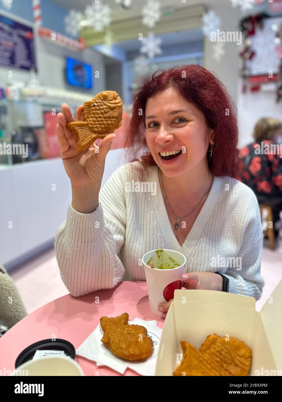 Woman with Japanese sweet taiyaki dessert. Freshly baked fish shaped waffle instead of filling adding ice cream. Winter and Christmas holidays sweets Stock Photo