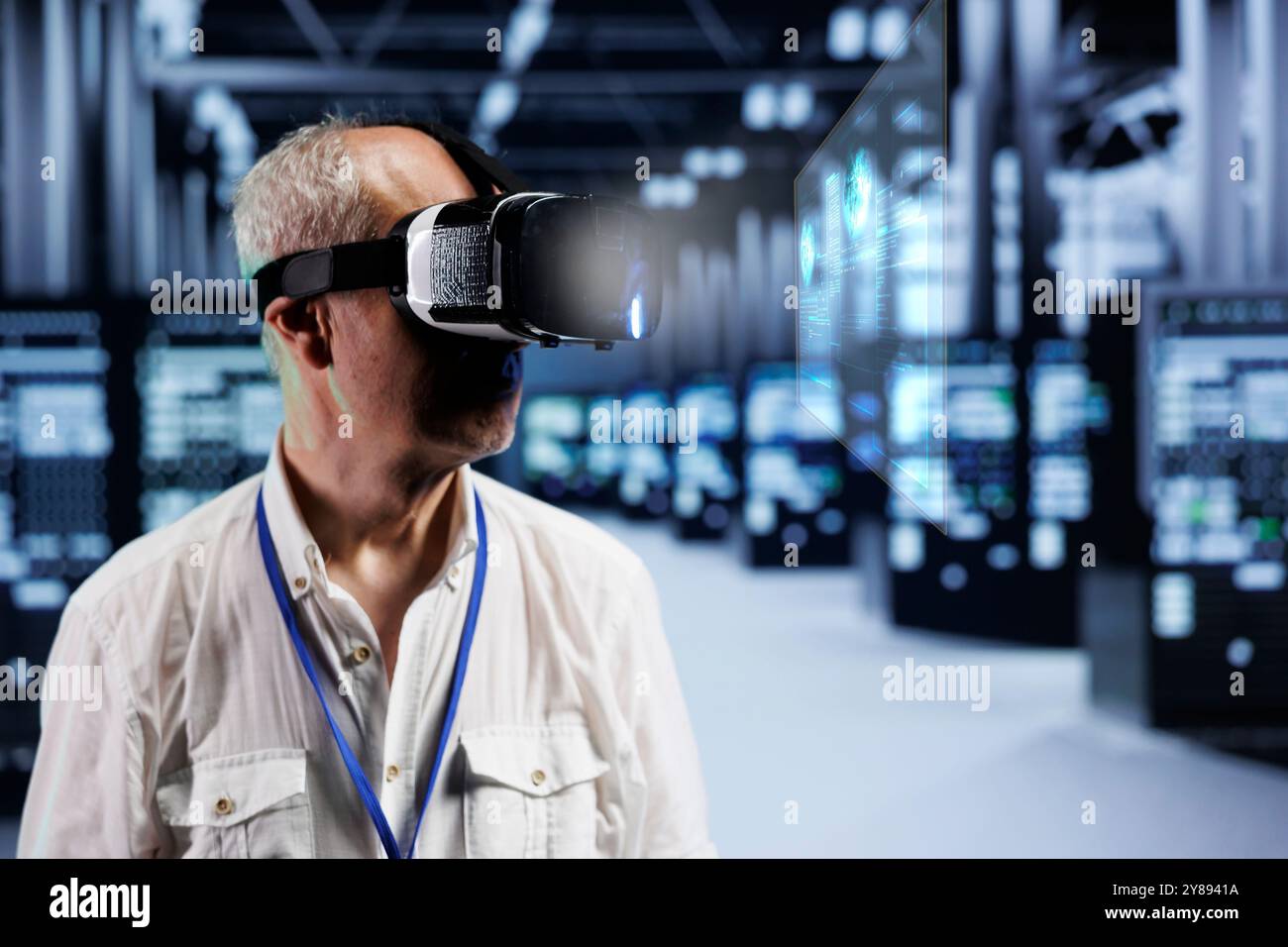 Old cloud computing business executive immersed in virtual reality at data center, doing equipment maintenance. Repairman using VR headset to optimize server rigs performance, checking code lines Stock Photo