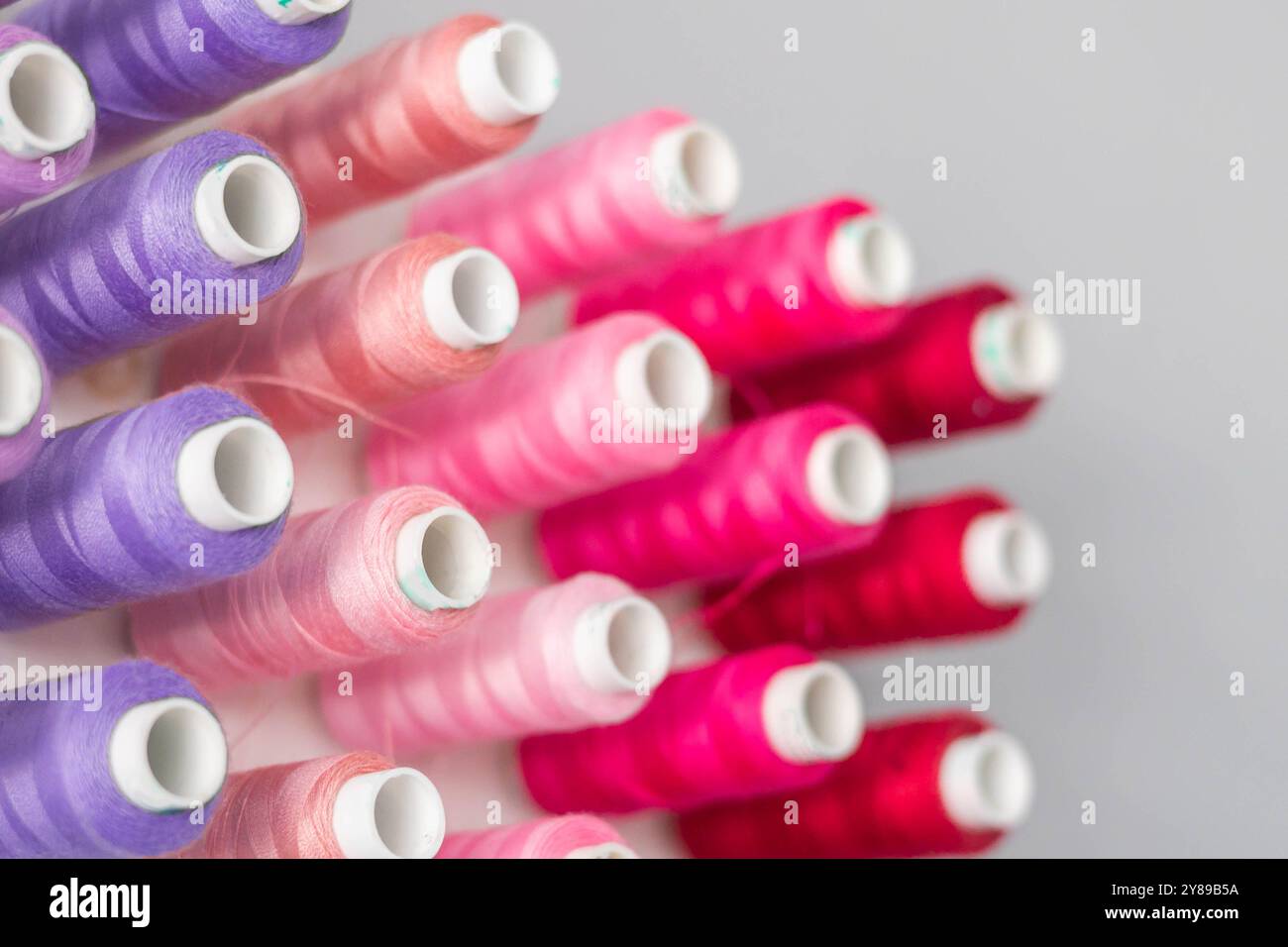 Multi-colored threads in spools and bobbins for sewing in a sewing workshop Stock Photo