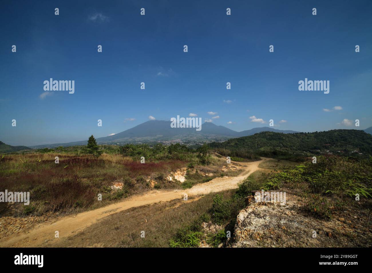 a dirt road with a mountain and blue sky Stock Photo - Alamy