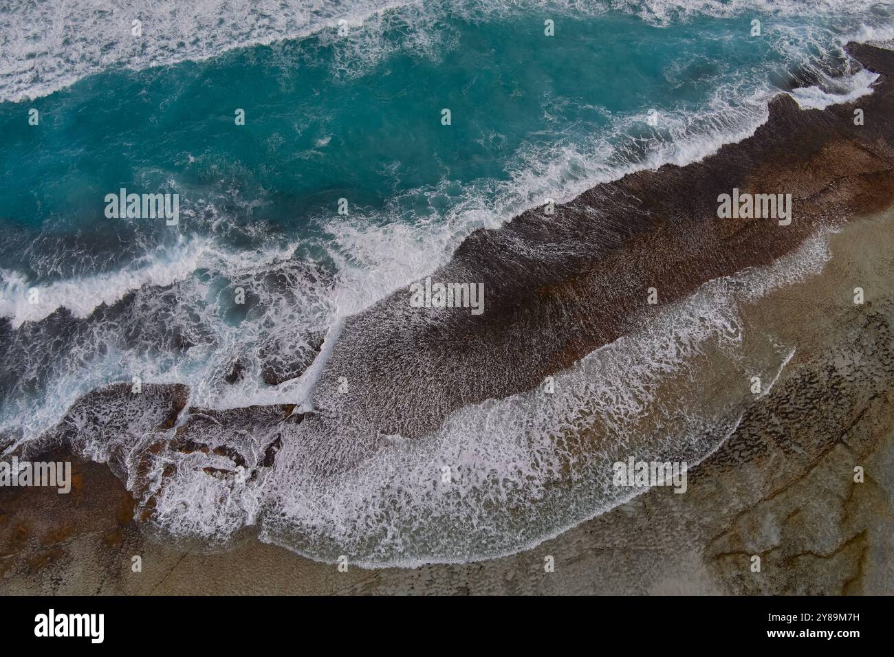Waves break as the cross a rocky reef Stock Photo