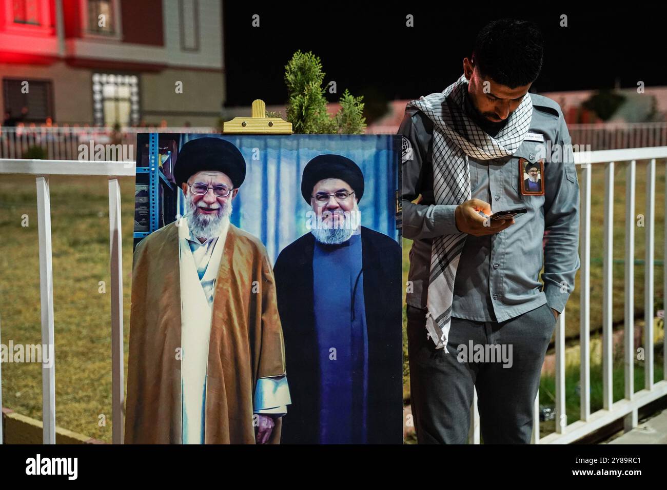 Bartella District, Iraq. 30th Sep, 2024. A man stands next to a banner include portraits of Iran's Supreme Leader Ayatollah Ali Khamenei (L), Hassan Nasrallah (R), during a memorial service for Hassan Nasrallah, the late leader of the Lebanese Shiite group Hezbollah who was killed in an Israeli airstrike in Beirut days ago, in Bartella district east of Mosul, northern Iraq. Credit: SOPA Images Limited/Alamy Live News Stock Photo